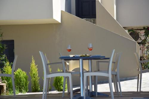 a table with three chairs and two glasses of wine at Amaryllis in Plataniás
