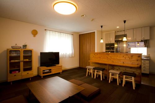 a living room with a kitchen and a counter with stools at Green Grass Hakuba in Hakuba