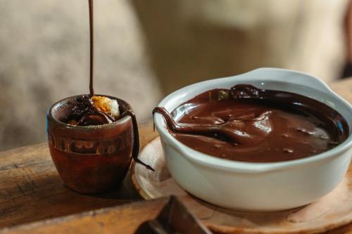 a bowl of chocolate next to a cup on a table at Bonding Coffee Roaster Café & Hotel in Quepos