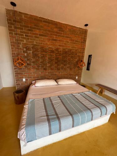 a bed in a room with a brick wall at Cabañas Mizontle in Mazunte