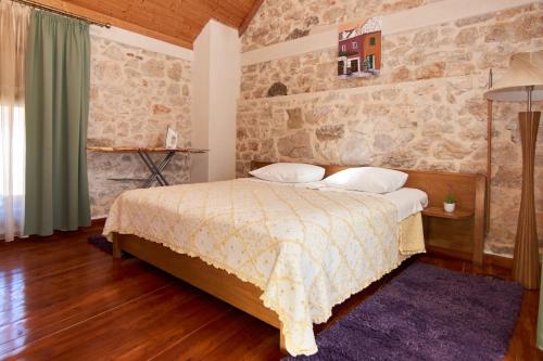 a bedroom with a bed and a stone wall at Seaside house for families with children Krapanj, Sibenik - 24166 in Šibenik