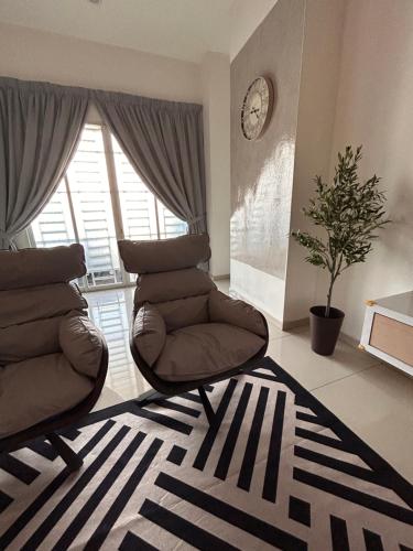 a living room with a chair and a clock on the wall at Naura Homes Penang in Kampong Batu Maung