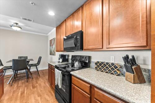 una cocina con armarios de madera y estufa negra en New Luxurious 1BR Apartment Heated Pool Spa & Sauna, en Reno