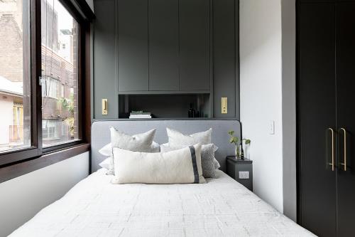 a bedroom with a white bed with black walls and a window at Regents Court Sydney in Sydney
