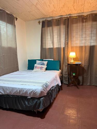 Un dormitorio con una cama y una mesa con una lámpara. en Casa DUNA 2, en La Libertad
