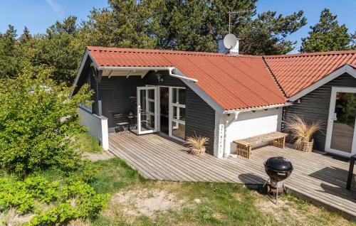 a house with a wooden deck with a bench at Three-Bedroom Holiday Home In Thisted in Nørre Vorupør