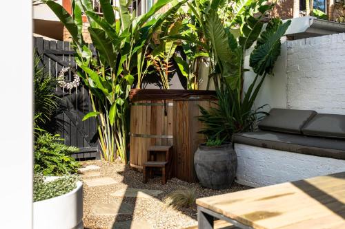 a patio with plants and a bench and a table at The Manly House - 100 steps from Manly Beach in Sydney
