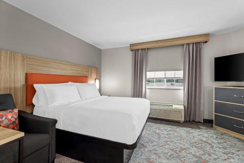 a hotel room with a bed and a television at Candlewood Suites Flowood, MS by IHG in Luckney