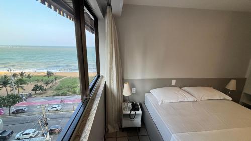 ヴィラ・ヴェーリャにあるFlats beira mar - praia da costaのベッドがあり海が見える寝室