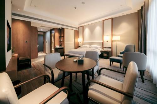 a hotel room with a bed and a table and chairs at Shangrao International Hotel in Shangrao