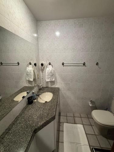a bathroom with two sinks and a toilet in it at Flats beira mar - praia da costa in Vila Velha