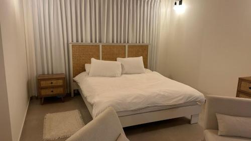 a bedroom with a bed with white sheets and pillows at סוויטות אוצר המעיינות in Reẖov