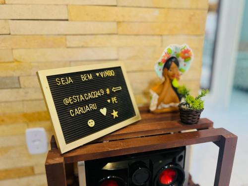 un cartello di lavagna su un tavolo con una statua di una donna di Estação 249 Caruaru (Casa de temporada) a Caruaru