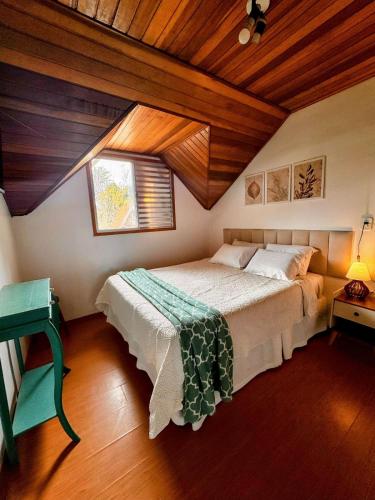 a bedroom with a bed and a wooden ceiling at Pousada Araucária Suítes in Campos do Jordão