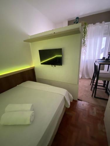 a bedroom with a bed and a table and a window at Kitnet compacta in Salvador
