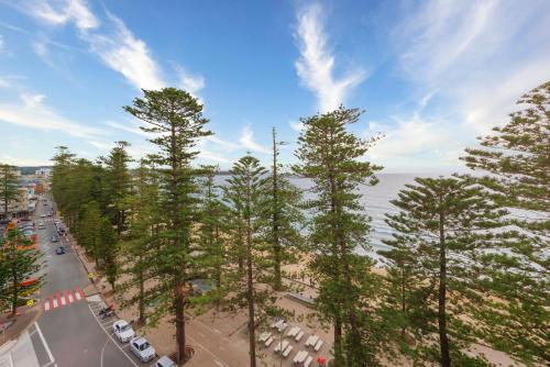 a view of a street with trees and the ocean at The Sebel Sydney Manly Beach in Sydney