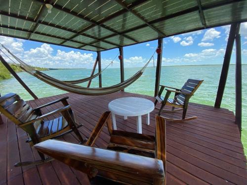 a porch with chairs and a hammock on the water at Coras Place Bacalar Lagoon front in Bacalar