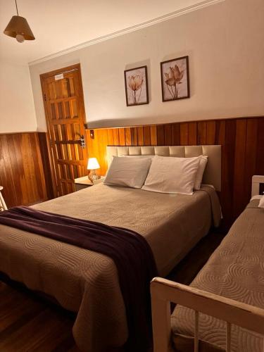 a bedroom with a large bed and two beds sidx sidx sidx at Pousada Araucária Suítes in Campos do Jordão