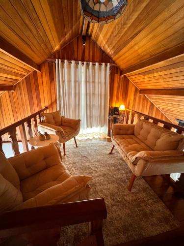 a living room with couches and a large window at Pousada Araucária Suítes in Campos do Jordão