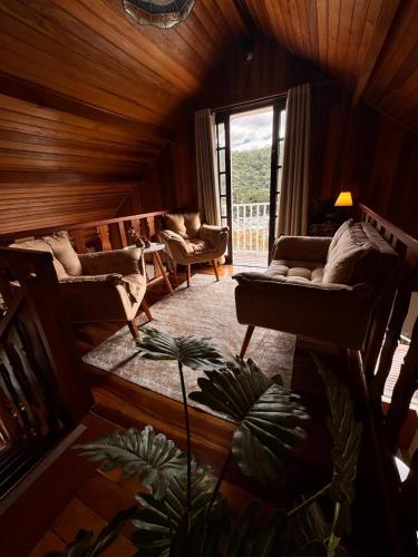 a living room with couches and a large window at Pousada Araucária Suítes in Campos do Jordão