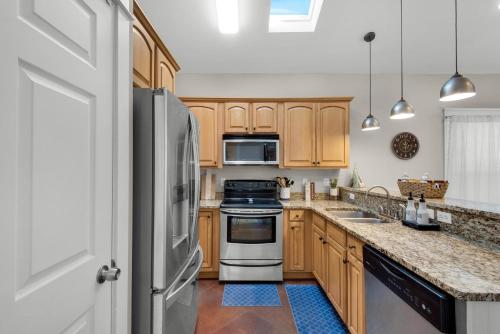 a kitchen with wooden cabinets and stainless steel appliances at Coastal Soul in Santa Rosa Beach