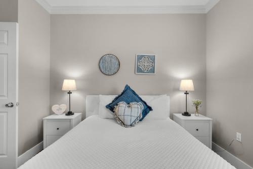 a white bedroom with a white bed with a blue pillow at Coastal Soul in Santa Rosa Beach