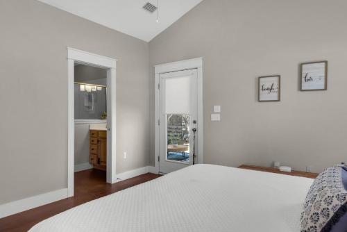 a white bedroom with a bed and a bathroom at Coastal Soul in Santa Rosa Beach