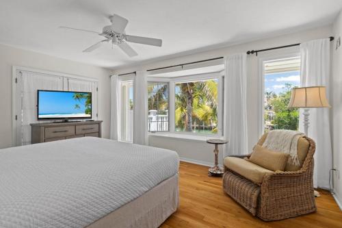 Un dormitorio con una cama y una silla y ventanas. en Gramma Dot's Marina House, en Sanibel