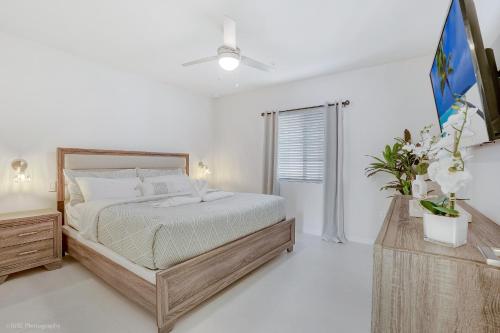 a white bedroom with a bed and a window at Beachside Bliss, 1BR Condo with Pool at Dania Beach in Dania Beach