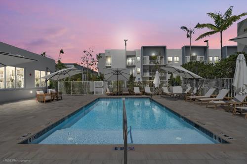a swimming pool with lounge chairs and a building at Beachside Bliss, 1BR Condo with Pool at Dania Beach in Dania Beach