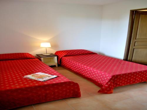 deux lits rouges dans une chambre avec une lampe dans l'établissement Apartment La Closerie Barjac III, à Barjac