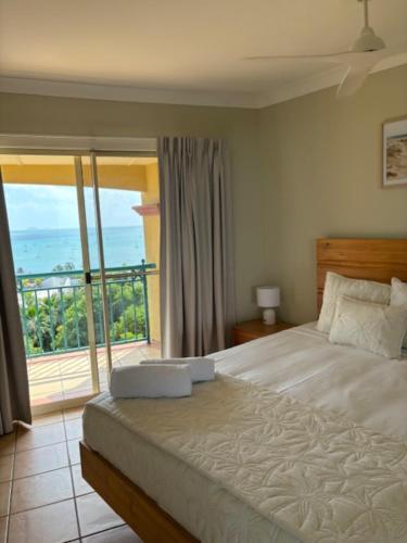 a bedroom with a bed with a view of the ocean at Toscana Village Resort in Airlie Beach