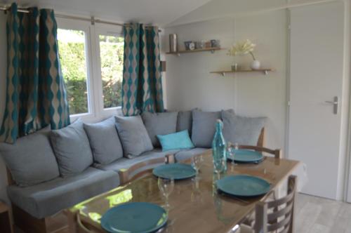 a living room with a couch and a table at Beau mobilhome La Palmyre 4 étoiles in Les Mathes