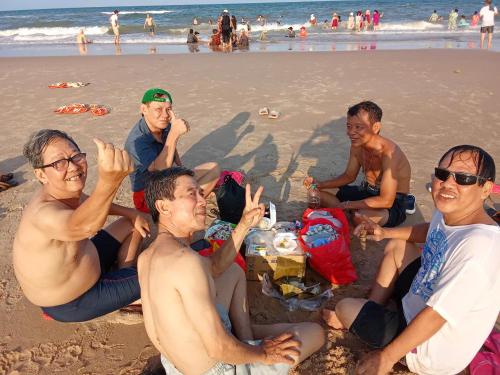 a group of men sitting on the beach at Texas Corner Garden Resort in Xóm Tram