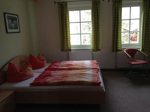 1 Schlafzimmer mit einem Bett mit roten Kissen und 2 Fenstern in der Unterkunft Landgasthaus am Dolgensee in Reichenwalde