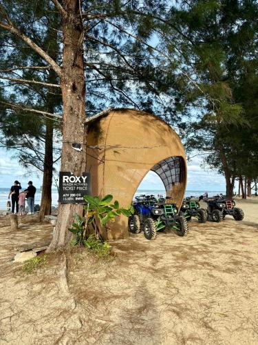 a group of motorcycles parked next to a tree on the beach at Roxy Sematan Beach Townhouse Deluxe , 1 & 2 in Sematan