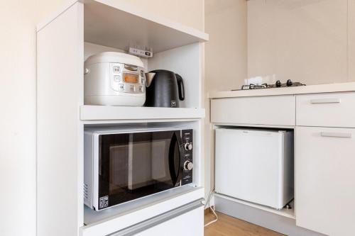 a white kitchen with a microwave oven and a appliance at Jintai House202 in Shiobaru
