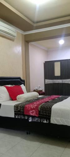 a bedroom with a bed with red and white sheets at Rezka Roomz Syari'ah in Ende