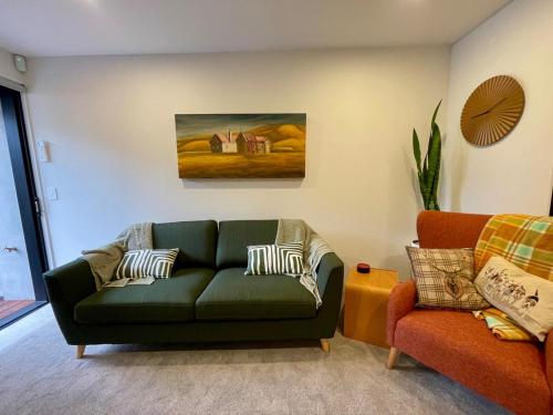 a living room with a green couch and a chair at Better than the rest - Central City Luxury in Christchurch