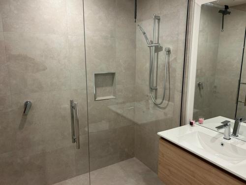 a shower with a glass door next to a sink at Better than the rest - Central City Luxury in Christchurch