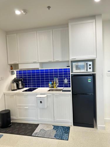 a kitchen with white cabinets and a black refrigerator at Hillside apartment sunset town city in Phu Quoc