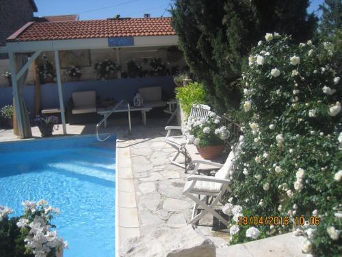 ein Pool mit Stühlen und ein Baum neben einem Haus in der Unterkunft Oinochori in Vouni