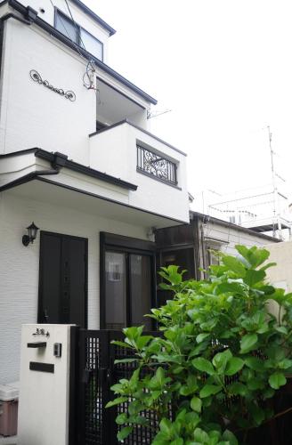 a white house with a door and a bush at Hanen半園 in Osaka