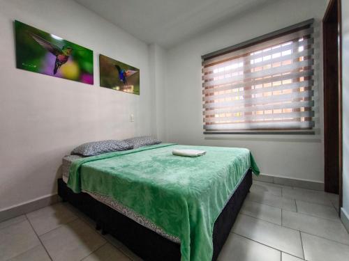 a bedroom with a bed with a green blanket on it at Apartamento nuevo en primer piso in Jardin