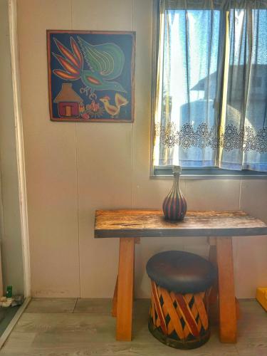 a table with a vase on it next to a window at Yellow house 6 minutos de playa in Barra de Navidad