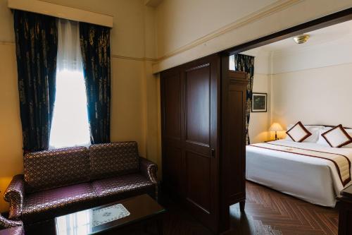 a hotel room with a bed and a chair at Du Parc Hotel Dalat in Da Lat