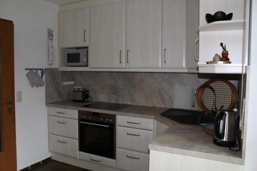 une cuisine avec des armoires blanches et un four à plaques de cuisson dans l'établissement Marschenblick-1, à Sankt Peter-Ording