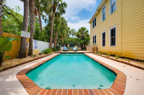 a swimming pool in front of a yellow house at Be A Nomad - Pool - 1bdr Just 1 Block to the Beach in Jacksonville Beach