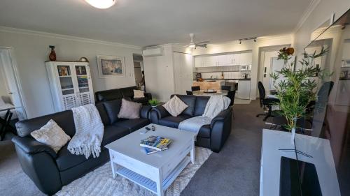a living room with a couch and a table at City Apartment 2xfree parking - Pool - Gym Wi-Fi in Perth
