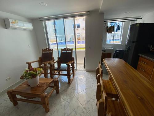 uma sala de estar com cadeiras e uma mesa e uma cozinha em Acojedor apto en coveñas em Coveñas